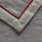 closeup of red colored embroidery on gray colored table runner for 6 seater table
