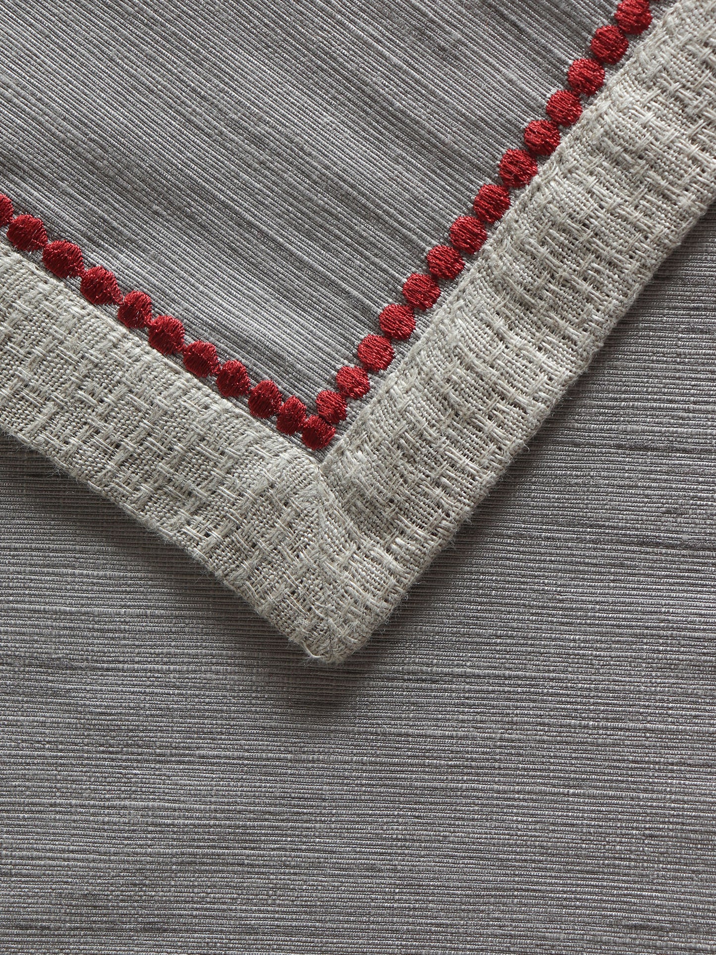 closeup of red colored embroidery on gray colored table runner for 6 seater table