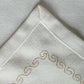 wavy patterned embroidery in golden color on an offwhite table runner