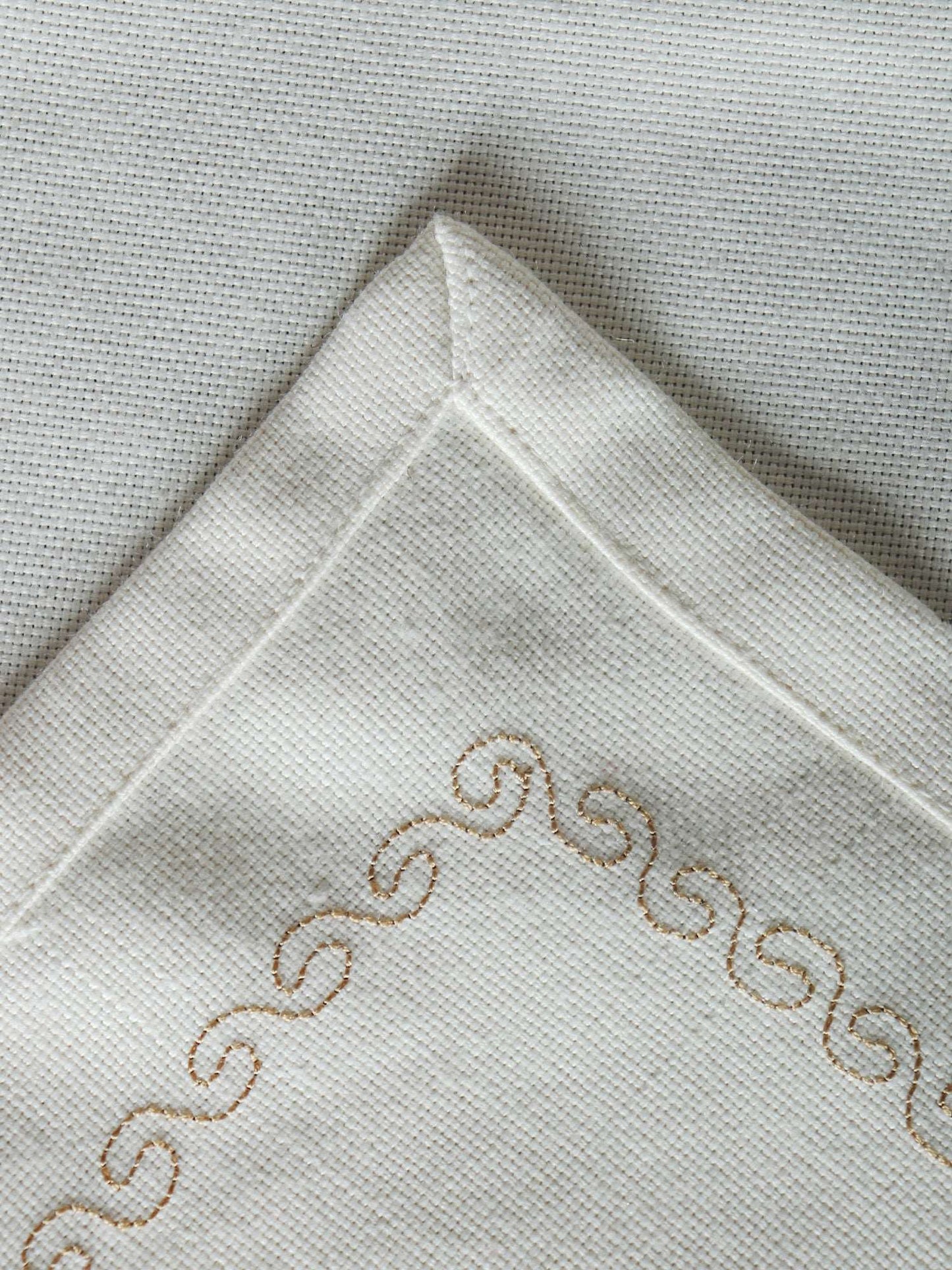 wavy patterned embroidery in golden color on an offwhite table runner