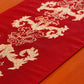 closeup of red colored embroidered table runner with tassels on corners for 6 seater table - 52x84 inches.