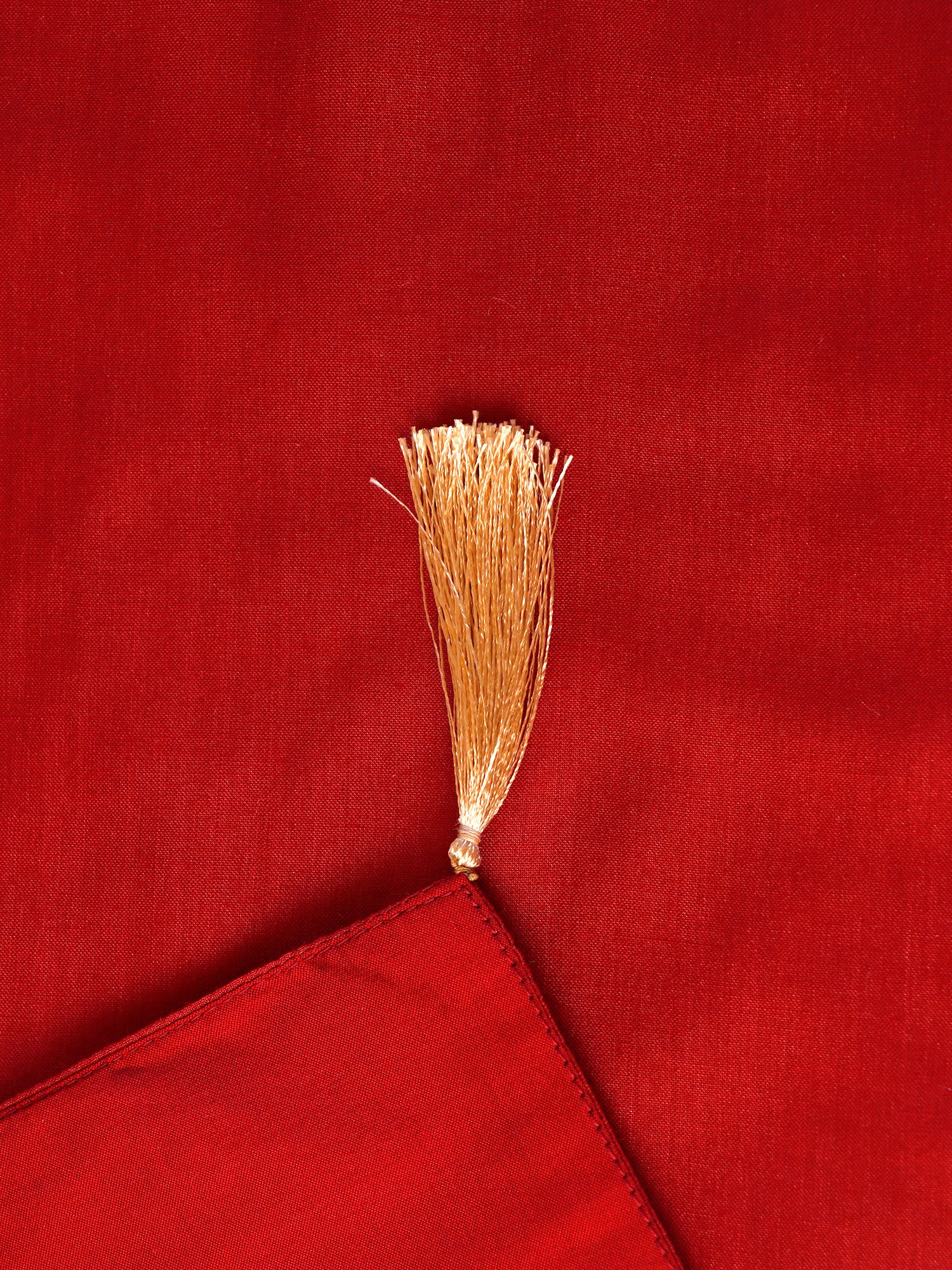 closeup of tassels on red colored embroidered table runner