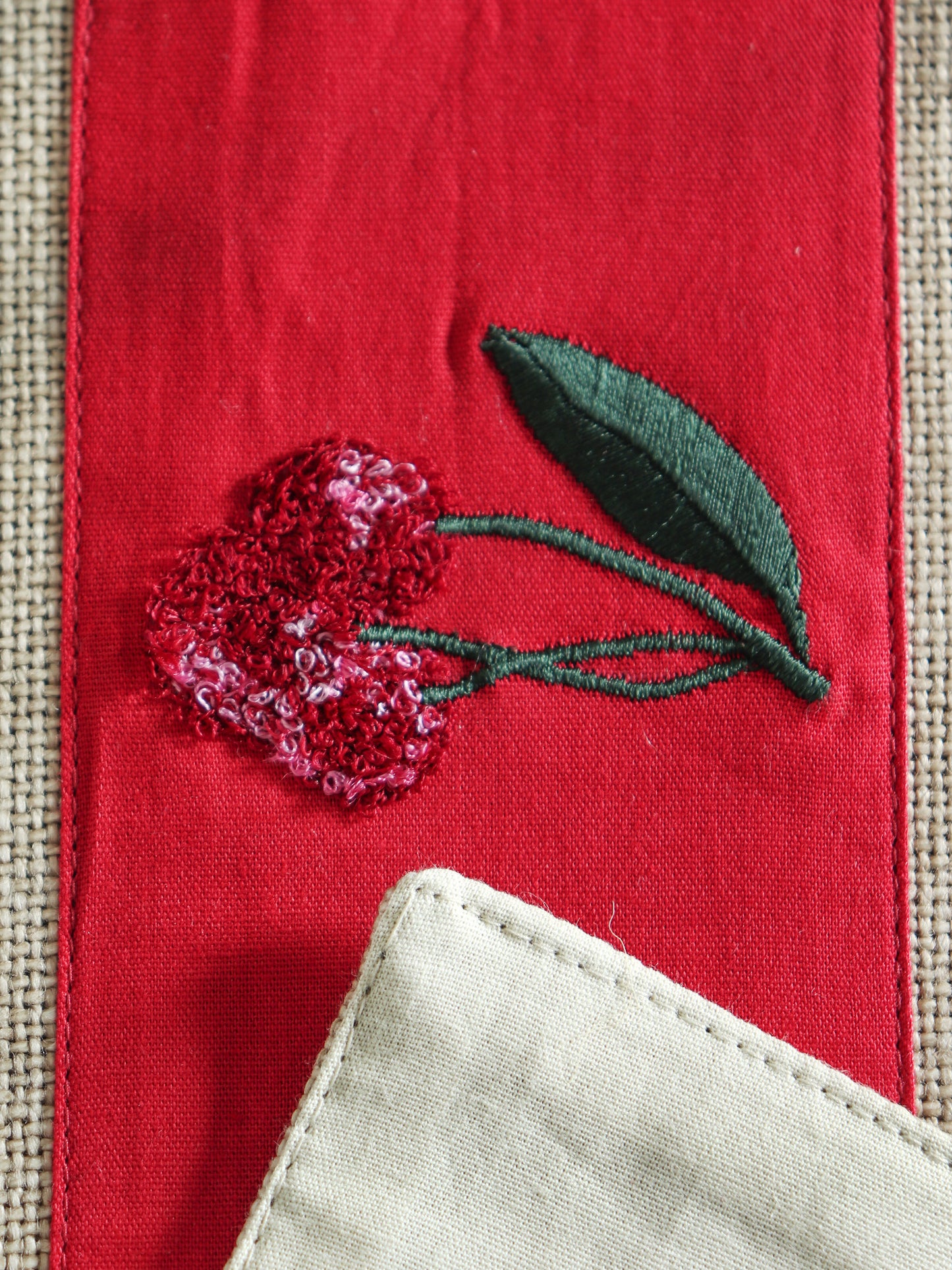 closeup of red floral embroidery in center patch on beige table runner for 6 seater dining table -  12x84 inches