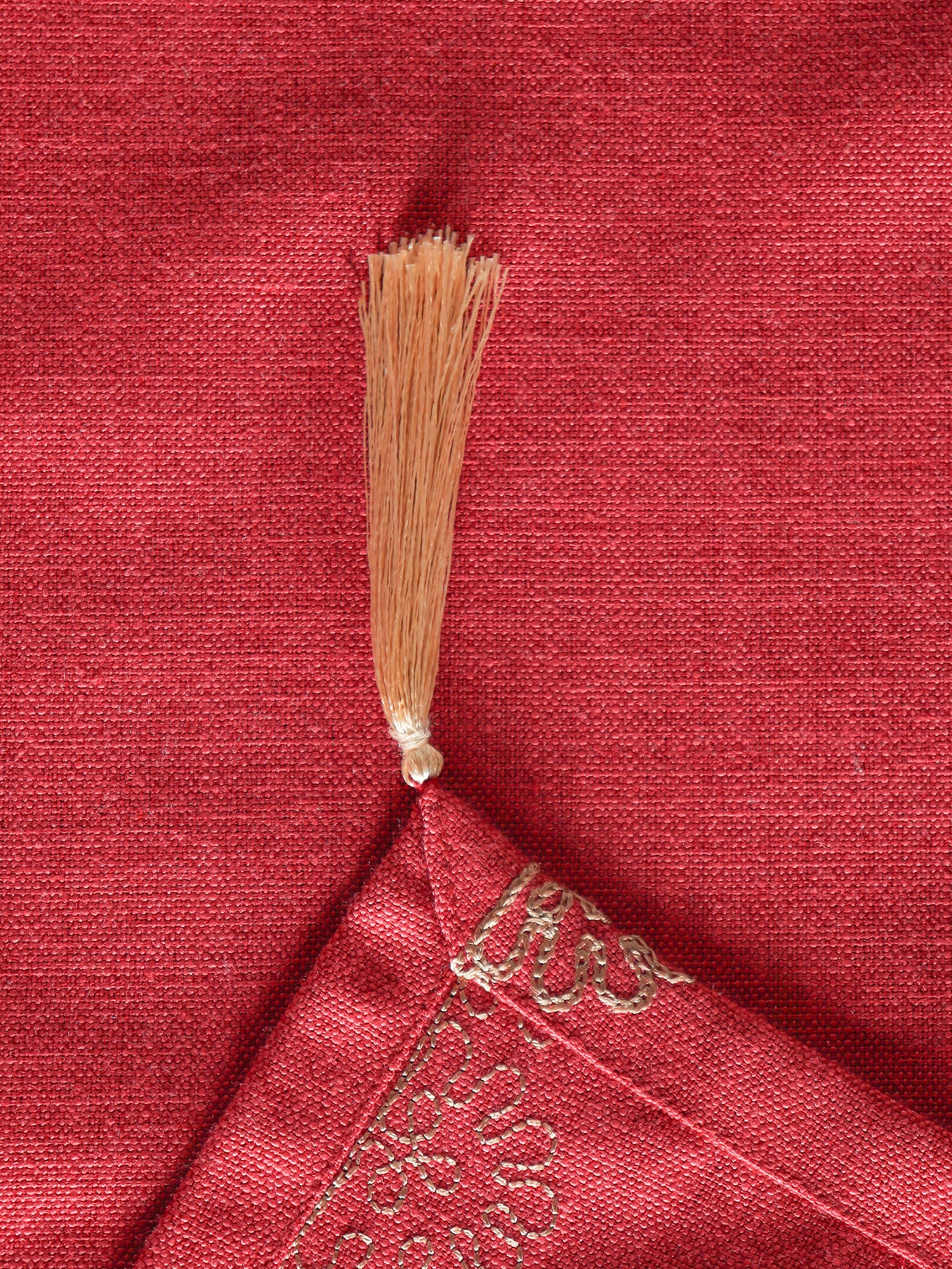 closeup of golden tassels on red colored tablerunner 