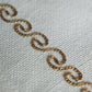 wavy patterned embroidery in golden color on an offwhite table runner
